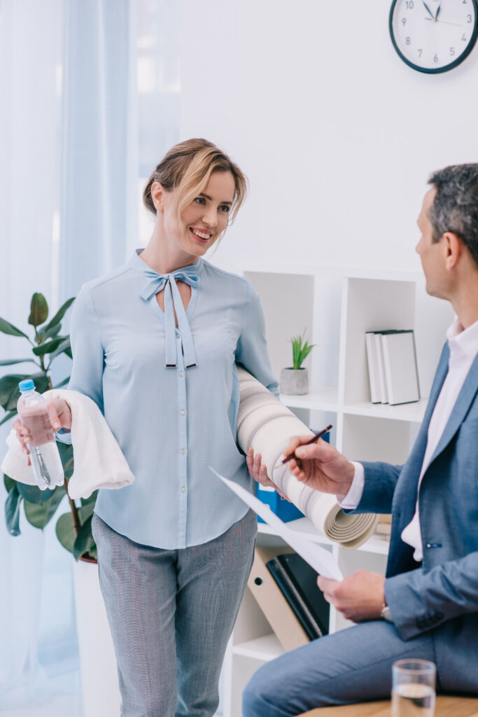 businesswoman with fitness equipment talking with colleague at office